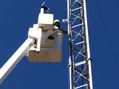 Lineman installing weather camera on tower.