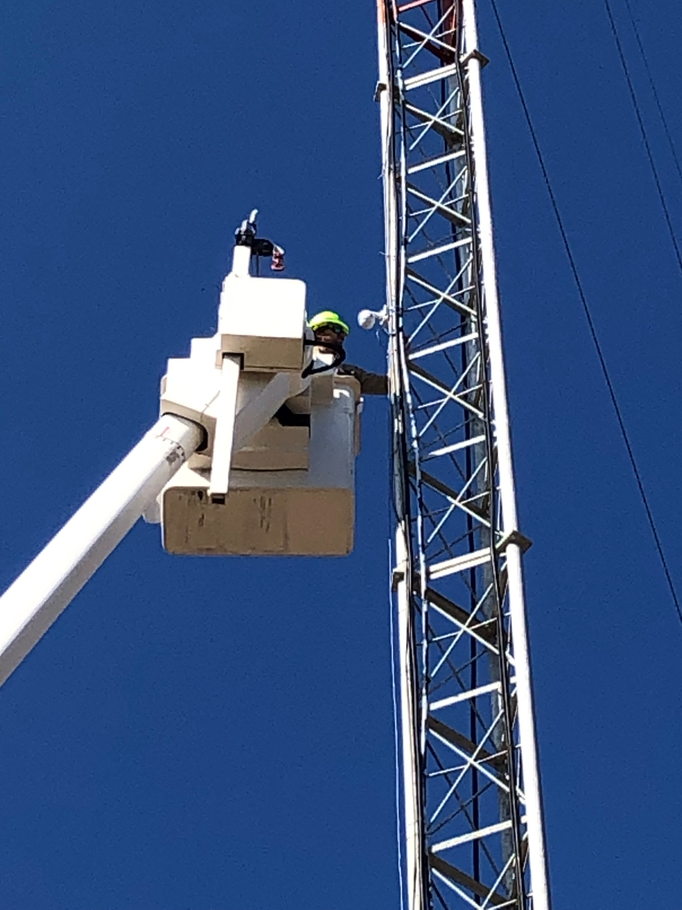 Lineman installing weather camera on tower.